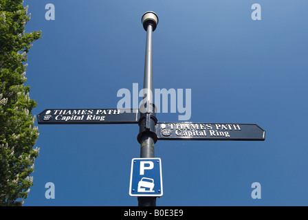 britische Laterne hält Zeichen markieren den Weg von der Hauptstadt Ring und Thames Path, auch mit einen blauen und weißen Parkplatz Schild Stockfoto