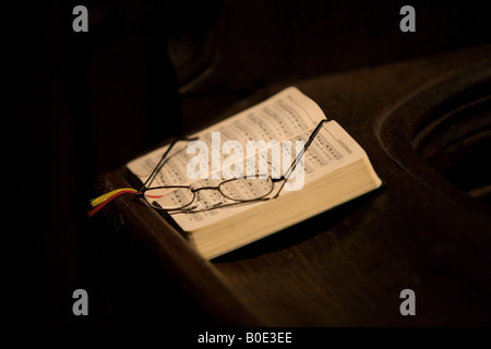 Ein Psalm-Buch und eine Reihe von Gläsern auf einer Bank in einer Kirche. Stockfoto