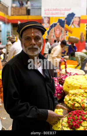 Eine Blumenverkäuferin in einem Hut steht in der Haupthalle der Stadtmarkt in Bangalore, Südindien. Stockfoto