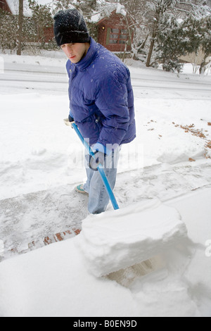 Ein männlicher Teenager Schaufeln Schnee nach einem Schneesturm Stockfoto