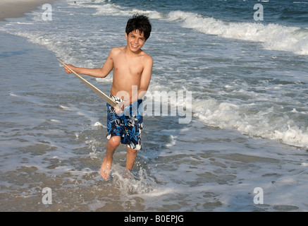 Ein kleiner Junge zu springen auf einem Skim Board an der Golfküste von Alabama. Stockfoto