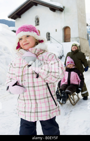 Kinder mit Schlitten im Schnee spielen Stockfoto