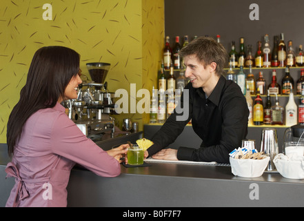 Junge Frau im Gespräch mit Barmann Stockfoto