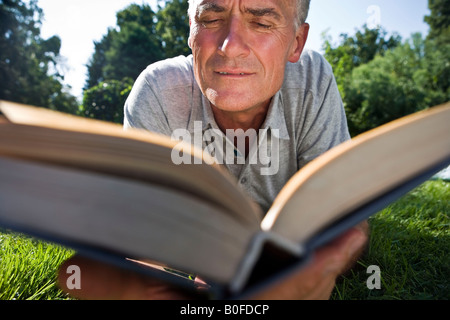 Mann liegt auf dem Rasen lesen Stockfoto