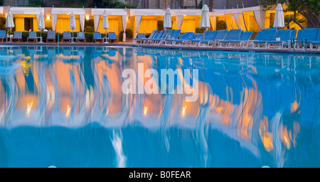 Resort Hotel-Schwimmbad mit wellenförmigen Motion Blur Reflexionen und Stuhl Lounges am Abend Stockfoto