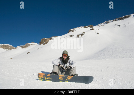 Snowboarder sitzend auf Schnee Stockfoto