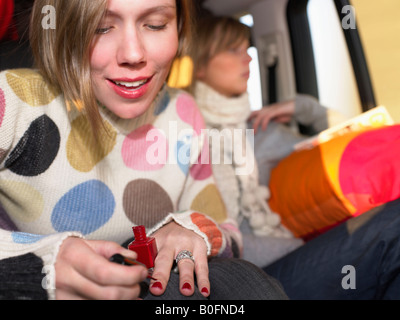 Junge Frau Malerei Nägel in Auto Stockfoto