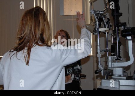 Eine Frau liest Zahlen und Buchstaben aus einem Distrance bei einer Augenuntersuchung. Stockfoto