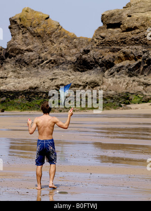 Junge Mann spielt mit einem Drachen auf einem sandigen Strand bei Ebbe Stockfoto
