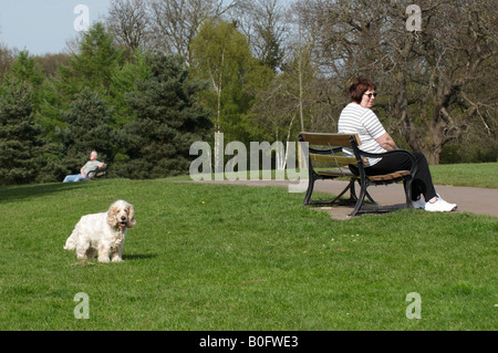 Frau sitzt auf der Bank mit Blick auf einen Weg mit Mann auf separaten Bank nur über die Hügel in der heißen Sommersonne in Vassalls parken Sie Bristol U Stockfoto