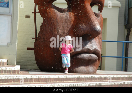 Kleines Mädchen vor dem Marlowe Theater mit riesiger Gesichtsskulptur The Friars Canterbury Kent Stockfoto