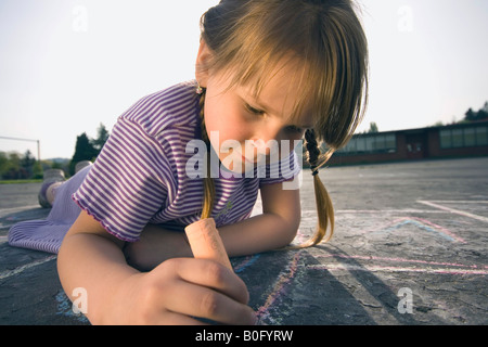 Junges Mädchen Festlegung auf Bürgersteig zeichnen mit Kreide. Stockfoto