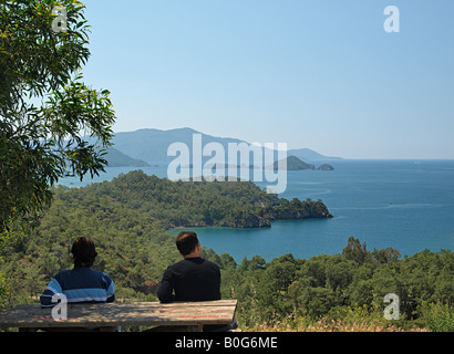 ZWEI TÜRKISCHE MÄNNER SITTNG AM TISCH AM AUSSICHTSPUNKT MIT BLICK AUF DEN GOLF VON FETHIYE AUS DER D400 GÖCEK FETHIYE ROAD, MUGLA, TÜRKEI Stockfoto