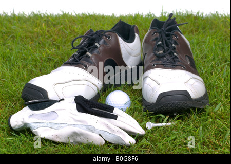Golfschuhe Handschuh Ball und Abschlag auf einige Rasen erschossen vor einem weißen Hintergrund Stockfoto