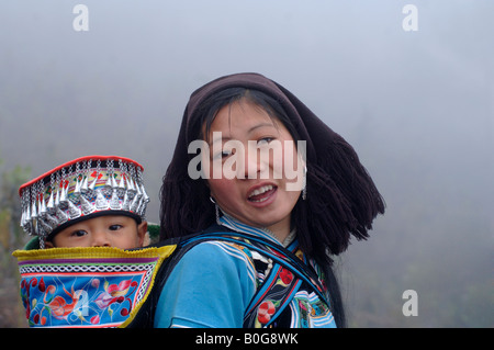 Mutter und Baby mit geschmückten Natur Motiven im frühen Morgennebel neben Reis-Terrassen in Yuanyang Yunnan China Stockfoto