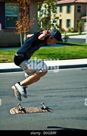 Ein California Teenager in der Luft Tricks auf der Straße auf seinem Skateboard zu tun Stockfoto