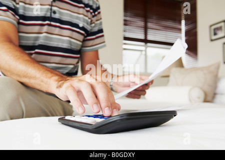 Des Mannes Hand summiert sich Rechnungen auf Rechner Stockfoto