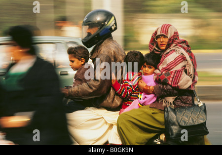 Ein Mann trägt einen Helm, den Transport von seiner Familie auf einem Roller, Pakistan. Stockfoto