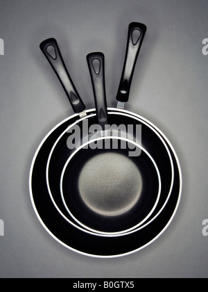 Drei Antihaft-Pfannen gestapelt auf einem grauen Hintergrund. Stockfoto