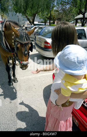 Mutter Holding Kleinkind, streckt ihre Hand zu einem Schlaganfall-Pferd in den Straßen in Mijas Pueblo, Costa Del Sol, Spanien Stockfoto