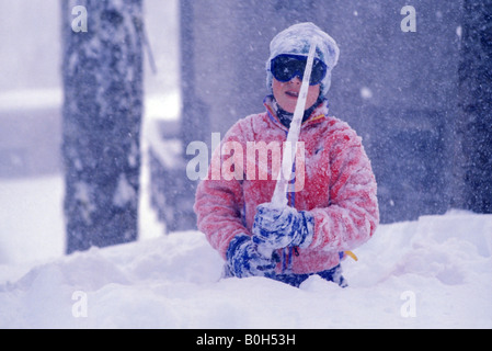 Ein zehn Jahre alter Junge einen großen Eiszapfen verwandelt sich in ein Schwert, als er bei einem schweren Schneesturm spielt Stockfoto