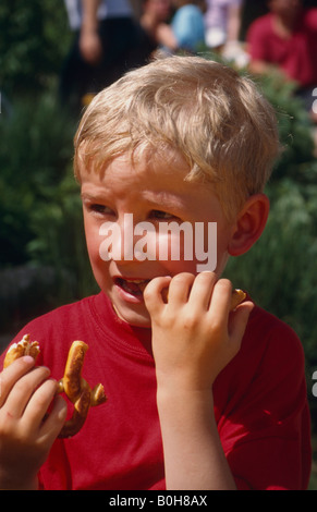 Vier-jähriger Junge eine Brezel zu essen Stockfoto