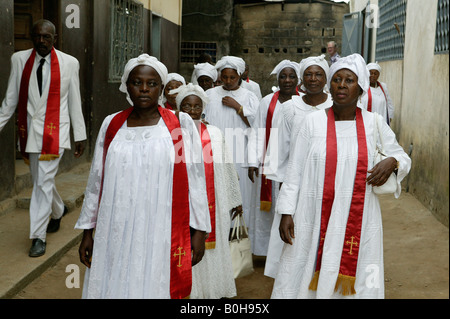 Frauen, gekleidet in weißen Gewändern und roten Schärpen an der Kirche in Douala, Kamerun, Afrika Stockfoto