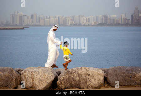 Vater und Sohn zu Fuß entlang einem Wellenbrecher, Abu Dhabi, ungebundene Arabische Emirate. Stockfoto