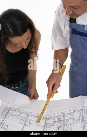 Arbeiter und eine Frau, die über Pläne, Baupläne Stockfoto