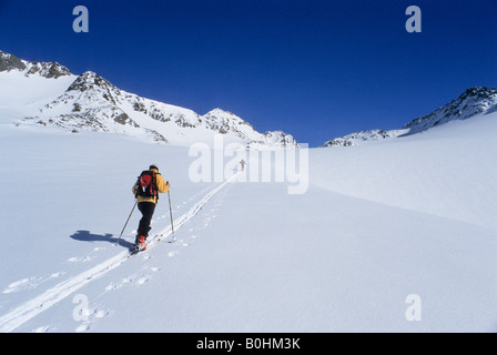 Tourengeher durchlaufen ein Touring verfolgen entlang einem breiten verschneiten alpinen Hochtal auf Mt. Similaun, Ötztaler Alpen, Tirol, Österreich, Euro Stockfoto