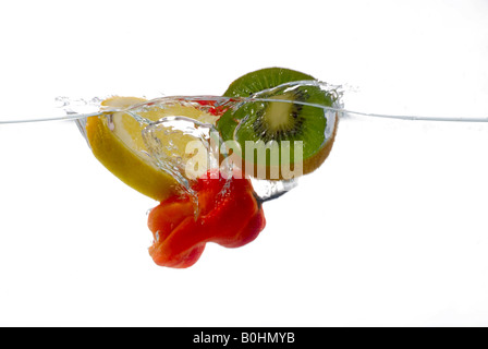 Scheiben der Zitrone, Kiwi und ein rotes hot Chili Pepper ins Wasser fallen Stockfoto