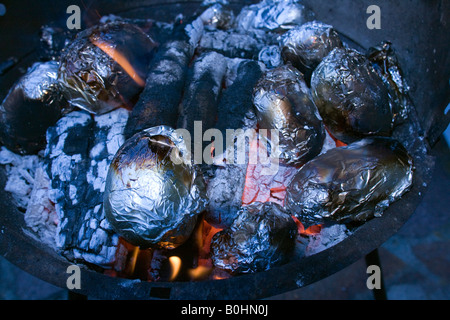 Gebackene Kartoffeln eingewickelt in Alufolie Backen auf heißen Kohlen, BBQ Stockfoto