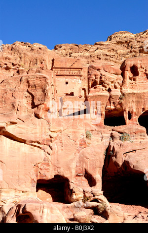 Vor kurzem bewohnten Höhlen in den geschichteten Lachs rosa und roten Sandsteinfelsen in Petra, Jordanien Stockfoto