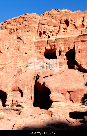 Vor kurzem bewohnten Höhlen in den geschichteten Lachs Rosa, graue & roten Sandsteinfelsen in Petra, Jordanien. Stockfoto