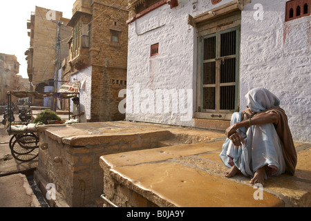 Eine alte Dame saß vor ihrer Tür nimmt im Morgenlicht in Jaisalmer, Rajasthan Indien Stockfoto