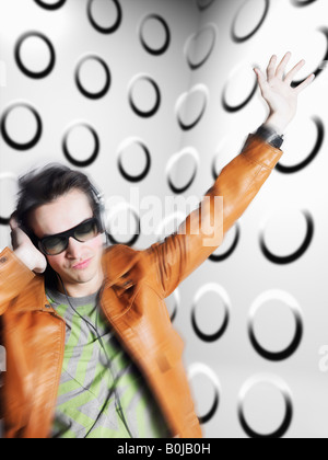Mann mit Kopfhörer und Sonnenbrille, Bewegungsunschärfe, vor fleckigen Wand Stockfoto