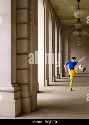 Fußball-Spieler treten Ball im Portikus Stockfoto