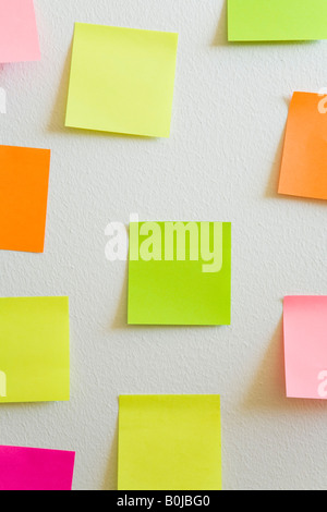 Leere Notizzettel an einer weißen Wand befestigt Stockfoto