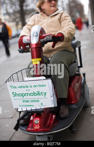 Rentner auf einen Shopmobility Roller in Cheltenham Stadtzentrum Stockfoto