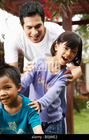 Vater und Kinder spielen im Garten Stockfoto