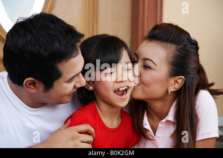 Eltern, die ihre Tochter auf die Wange küssen Stockfoto