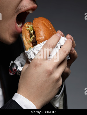 Geschäftsmann Essen Hamburger Stockfoto