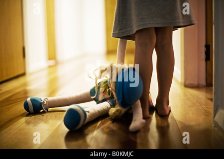 Mädchen im Alter von vier Jahren trägt Spielzeugpuppe in Halle Stockfoto
