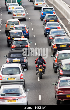 Motorradfahrer rutscht durch zwei Fahrspuren von Staus auf der Autobahn M25 London Vereinigtes Königreich Stockfoto