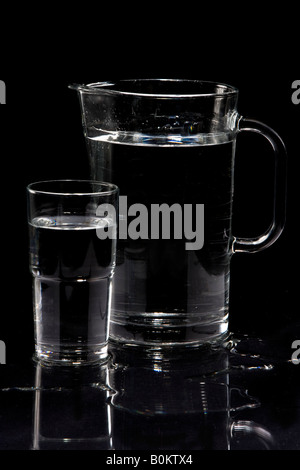 Kann mit frischem Wasser in einen Krug aus Glas. Isoliert auf schwarz Stockfoto