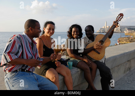Zwei Frauen und zwei Männer auf einer Mauer sitzend und spielen ihre Instrumente am Melacon Boulevard in Havanna Kuba April 2007 Stockfoto