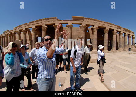 Ein ägyptischer Reiseleiter mit Touristen durch die Kolonnade am Tempel der Isis Komplex auf der Insel Philae in der Nähe von Assuan, Ägypten Stockfoto