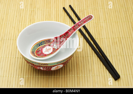 Chinesisch (traditionell) Schale, Löffel und Stäbchen auf Bambusmatte angeordnet Stockfoto