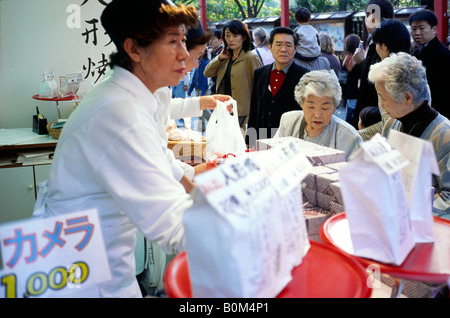 Zwei ältere japanische Damen kaufen Sie traditionelle Köstlichkeiten auf der Nakamise Dori in Tokio Asakusa. Stockfoto