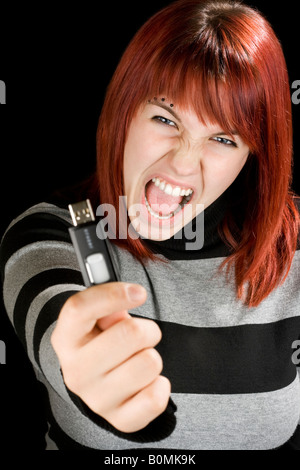 Schöne rothaarige Mädchen hält einen USB-Stick oder USB-Stick an der Kamera mit einem wütenden Ausdruck Studioaufnahme Stockfoto